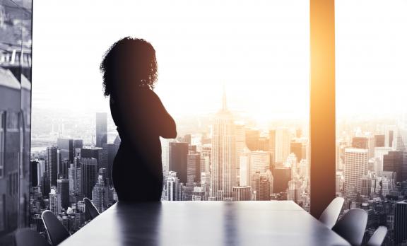 Woman looking out over cityscape at sunrise.