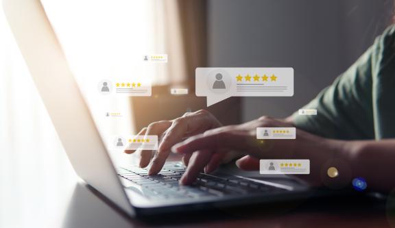 person typing on a computer with online review graphics