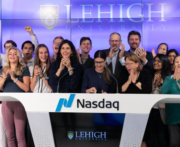 Samantha Dewalt, managing director of the Lehigh@NasdaqCenter, rings the opening bell of the Nasdaq Market, flanked by Lehigh students. 