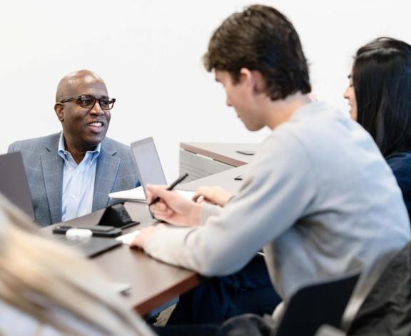 Ozias Moore, associate professor of management, interacts with students during his Leadership in Organizations course