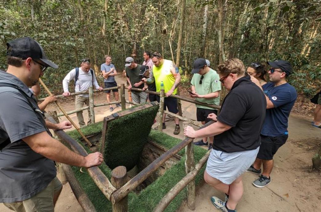FLEX MBA students gathered around a tunnel entrance in Vietnam on global immersion trip.